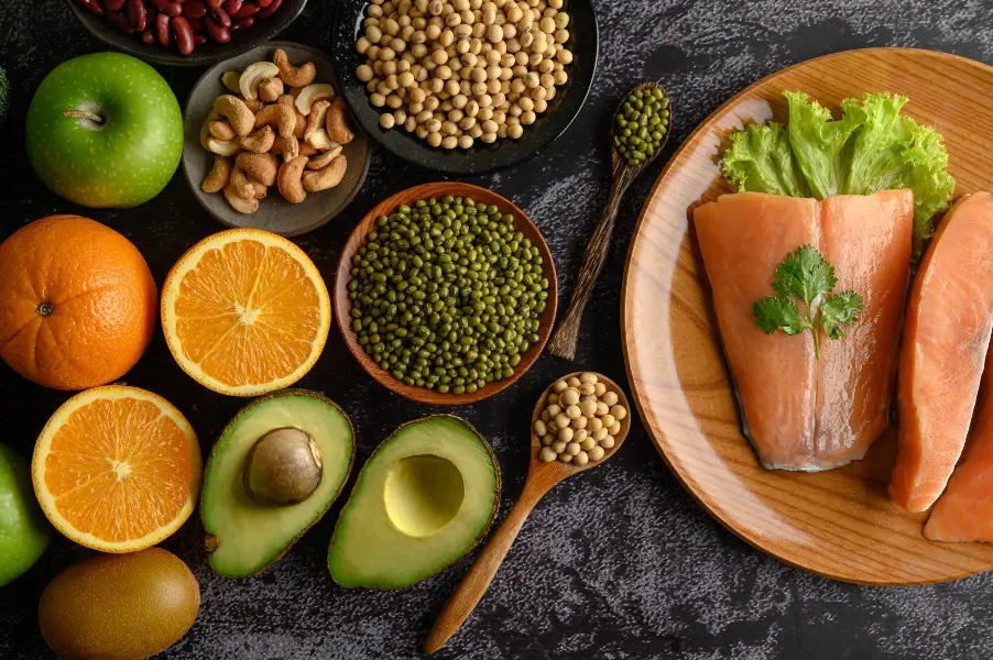 Legumes, fruit and salmon pieces on a wooden plate.