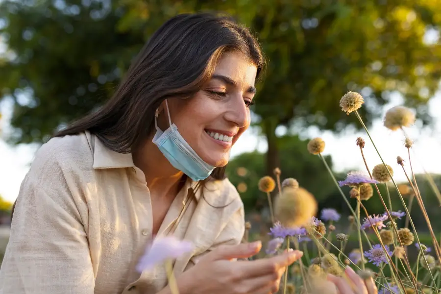 Side view smiley woman smelling flowers